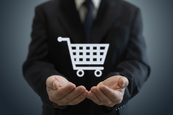 E-Commerce-Manager hält virtuellen Einkaufswagen in den Händen