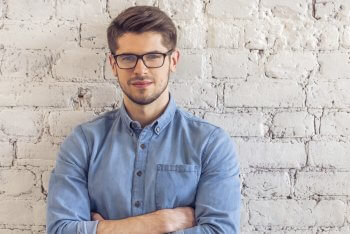 Marketingberufe Übersicht Ein Marketing-Mitarbeiter steht mit verschränkten Armen vor einer Wand.