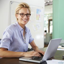 Eine Social-Media-Managerin sitzt an ihrem Arbeitsplatz vor ihrem Laptop.