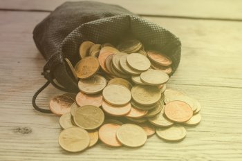 Ein mit Münzen gefülltes Säckchen liegt auf einem Tisch.