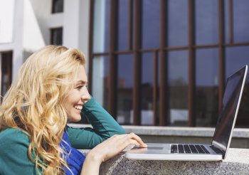 Marketing Fernstudium Übersicht Eine Studentin betrachtet lachend etwas auf ihrem Laptop.